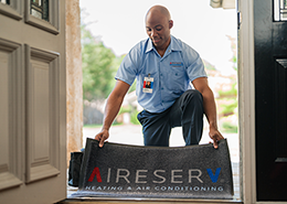 An Aire Serv professional laying a mat outside a customer's home.