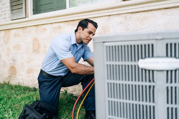 Male technician working large outdoor HVAC unit.