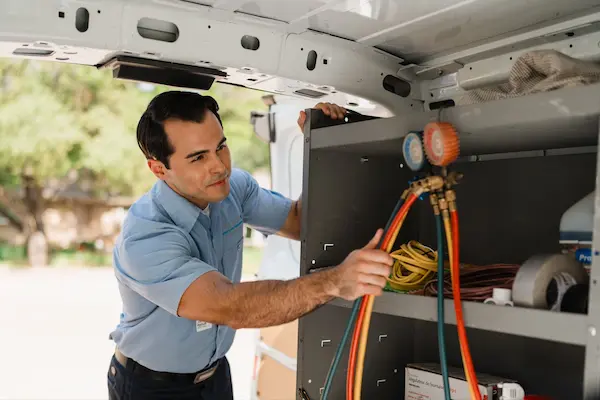 Male HVAC technician grabbing manifold gauge from van.