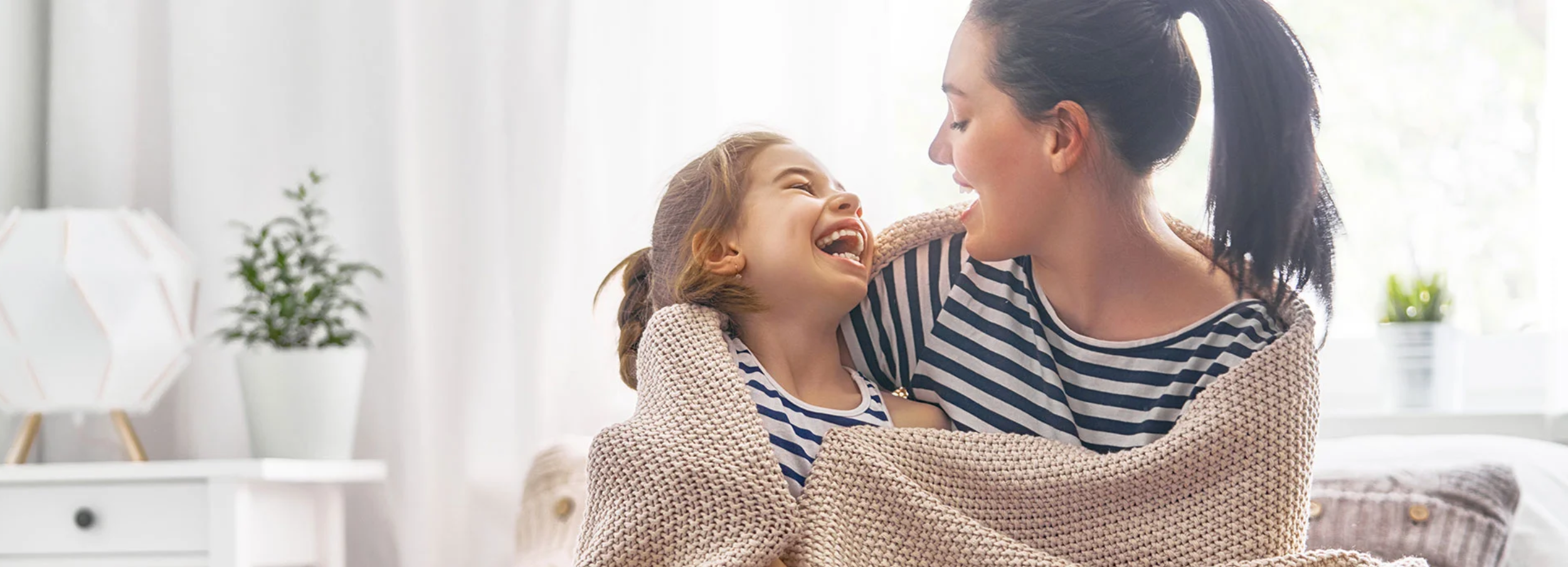 Laughing mother and daughter wrapped in a blanket.